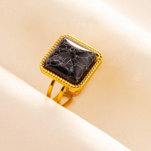 Detailed close-up of a vintage square black stone ring on elegant beige satin fabric
