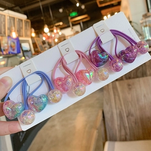 Detailed view of colorful heart-shaped hair ties with glitter beads on display card