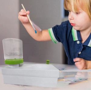 Close-up of a child cleaning a brush in an automatic water cycle brush cleaner system