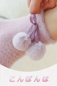 Detail of pink fleece socks featuring a purple satin bow and soft hanging pom-poms