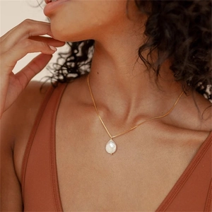 Détail d'un pendentif en perle baroque naturelle sur une fine chaîne dorée élégante