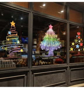 Detail showing colorful Christmas tree window stickers with Merry Christmas text on glass