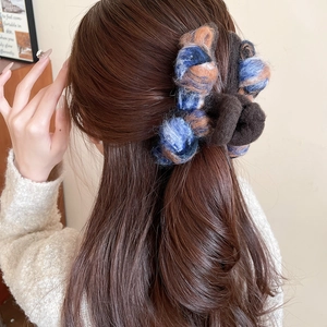 Detail view of a fuzzy mix-color claw clip styled in a classic bun on brown hair