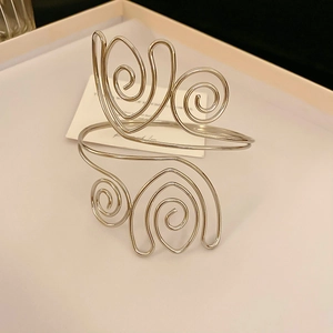 Detalle de brazalete plateado ondulado con diseño hueco y textura espiral elegante