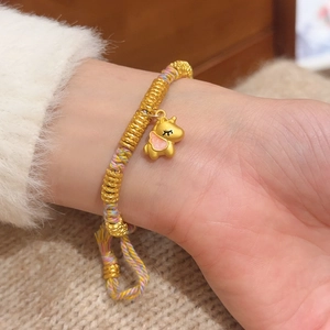 Close-up of a woven rainbow rope bracelet featuring a golden unicorn charm and beads