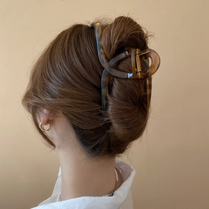 Close-up of a large leopard print hair claw clip securing a chic updo hairstyle