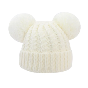 Detail of baby knitted hat with cable stitch texture and fluffy double faux fur pom-poms