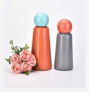 Gros plan de flacons décoratifs minimalistes orange et gris avec bouchons sphériques sur blanc