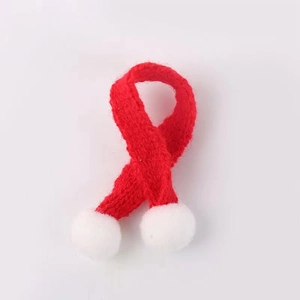 Detailed view of a red knitted mini scarf with white pom-poms for DIY Christmas decor