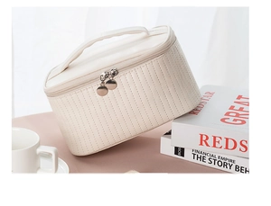 Detail of beige quilted leather makeup bag with gold zippers and top carry handle