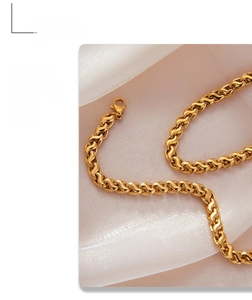 Detail of high-gloss gold twisted chain necklace on soft pink silk background