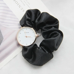 Detail of elegant watch with black silk ribbon strap and rose gold bezel on a magazine