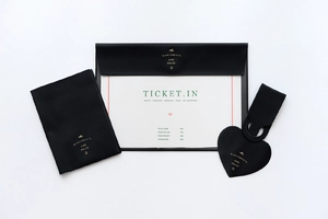 Close-up of black faux leather ticket organizer set with gold lettering and luggage tag