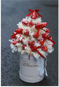 Close-up of strawberry bouquet in white round box with red ribbon and feather accents