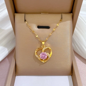 Detailed view of a gold heart necklace with a pink gemstone in a luxury gift box