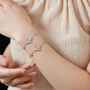 Close-up of gold and silver clover bracelets with sparkling zircons on a model wrist
