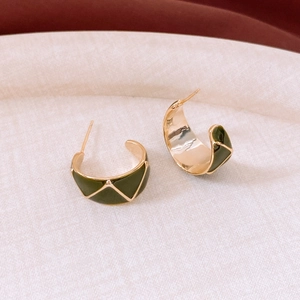 Detail of vintage 18k gold C-shaped earrings with green geometric enamel texture