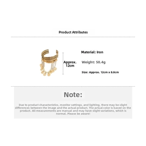 Detail of gold metal arm cuff featuring bohemian fringe discs and engraved patterns