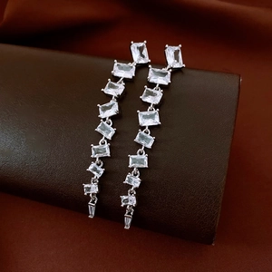 Détail de boucles d'oreilles argentées avec pampilles en zircon baguette sur support