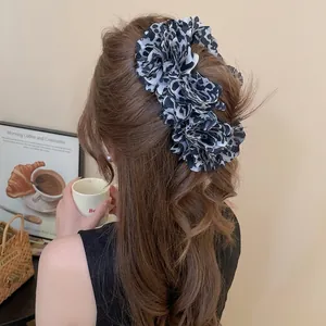 Elegant large leopard print fabric flower hair clip worn on back of head for styling
