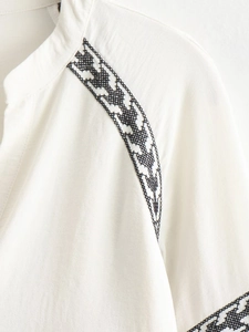 Close-up of black geometric embroidery on white linen cotton blouse for women