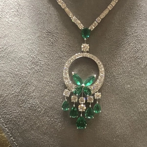 Dettaglio di pendente in argento con pietre verde smeraldo e accenti di diamanti