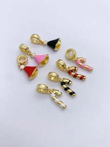 Detail of Christmas bell and candy cane charms in gold plating and colorful enamel finish