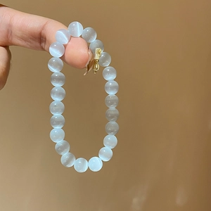 Close-up of pale blue cat eye stone beaded bracelet showing glossy light-reflecting bands
