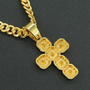 Macro shot of gold cross pendant with textured finish on a stylish Cuban link chain