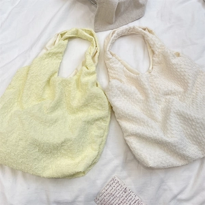 Detailed texture of pale yellow and off-white bubble fabric tote bags in a minimalist style