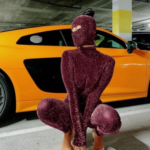 Vue détaillée du body pailleté bordeaux et cagoule assortie devant une voiture de sport
