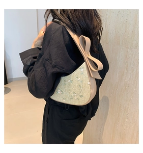 Detail of summer straw bucket bag with floral embroidery and bow knot shoulder strap