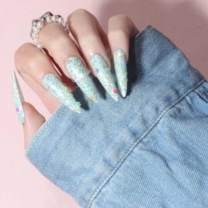 Detail of long stiletto press-on nails with colorful glitter and blue sequins