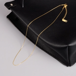 Macro detail of 18K gold thin chain necklace with lobster clasp and K18 tag