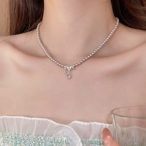 Détail du collier de perles rose argenté avec pendentif en zircon sur le cou du modèle