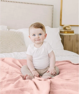 Detailed waffle texture of soft pink cotton baby blanket used in a cozy home setting