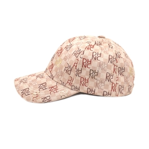 Detail view of beige baseball cap with repeating PH NC letter print and textured fabric