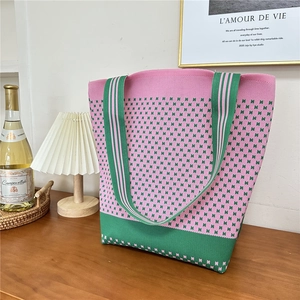 Detailed knit shoulder tote bag with pink and green houndstooth pattern on a table