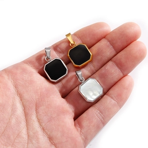 Dettaglio di tre ciondoli geometrici ottagonali in nero e bianco con cornici in metallo