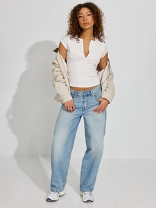 Detail of white ribbed knit short-sleeve top paired with blue denim jeans and beige jacket