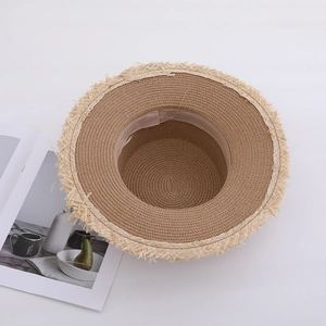 Straw sun hat with frayed edge and lace detail on white background for beach vacation