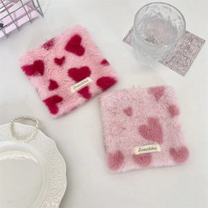 Macro detail of plush heart pattern coasters with soft faux fur texture and branded tag