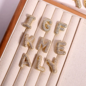 Détail de pendentifs lettres bulles sertis de zircons cubiques avec finition or 18K
