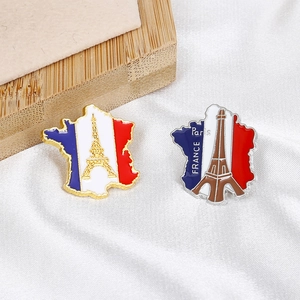 Détail de broches en émail carte de France et Tour Eiffel sur fond de soie blanche