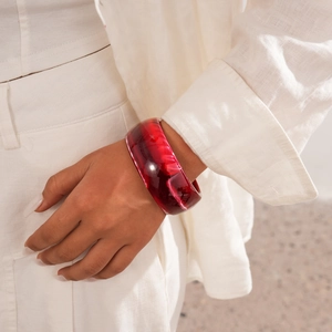Close-up of red marble resin wide cuff bracelet on model's wrist with polished finish