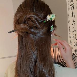 Detail of wooden butterfly hair stick with jade ring and flower tassel on bun