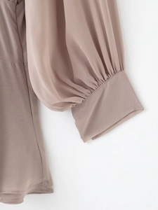 Détail des manches longues avec poignets froncés sur une robe fluide en mousseline rose