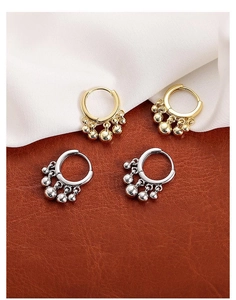 Detailed view of gold and silver hoop earrings with dangling beads on a textured base