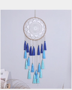 Macro detail of hand-woven white crochet patterns on a blue tassel dreamcatcher