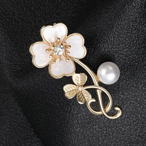 Detail of golden clover brooch with white shell petals, crystals and a large pearl
